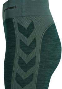 Gröna leggings med en texturerad design i sicksackmönster, tillverkade av stretchigt tyg som framhäver en figurnära siluett.