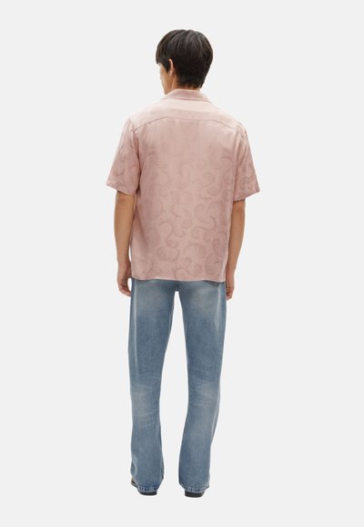 Korte mouwen roze shirt met een subtiele paisleyprint, gecombineerd met lichtblauwe jeans, gezien vanaf de achterkant. Casual fit, zachte stof.