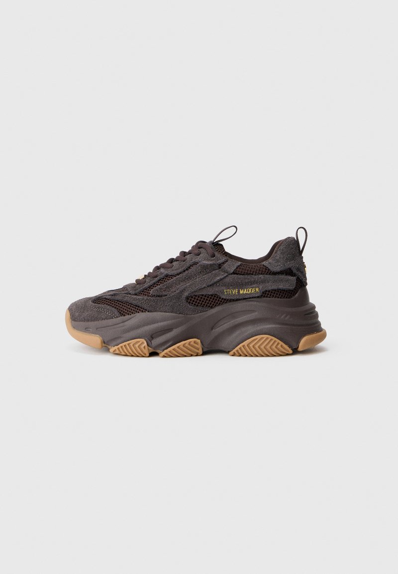 Pantofi sport cu un superior din plasă gri închis și accente din suede, având o talpă robustă din cauciuc de culoare bej. Detaliu cu logo auriu pe latură.