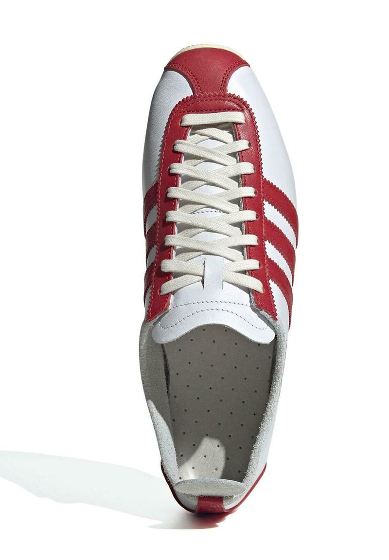 Weiße Ledersneaker mit roten Akzenten, runder Zehenpartie, flachen beigen Schnürsenkeln und drei roten Streifen an der Seite. Innenfutter aus Wildleder.