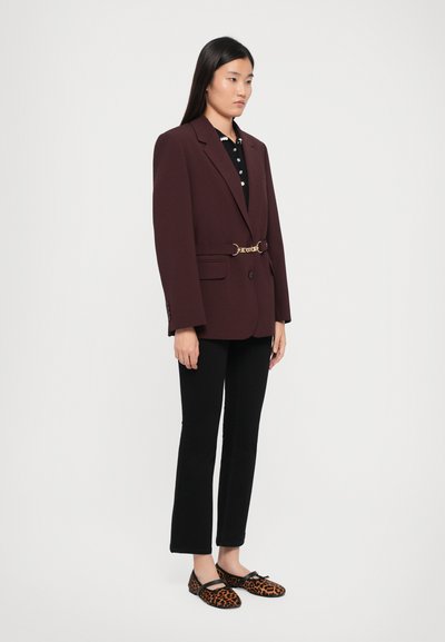 Maroon blazer with gold hardware belt, paired with black top and flared black pants. Leopard print shoes complete the look.