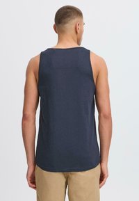 Marineblå bomulds tanktop med rund halsudskæring og ærmeløs design. Har en lige kant og minimale syninger.
