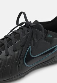 Sorte fodboldstøvler med struktureret syntetisk overdel, har mørkeblå accenter og Nike-logo. Snørebåndsdesign og polstret krave.