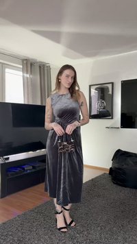 Szara sukienka z aksamitu z dopasowaną górą i zwiewną spódnicą. Dodatki to mała czarna torebka z białym wzorem oraz czarne sandały na paskach.