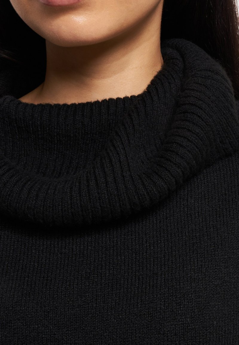 Czarny sweter z kołnierzem typu golf, posiadający prążkowaną teksturę i szeroki, złożony kołnierz, podkreślający miękki i ciepły wygląd materiału.