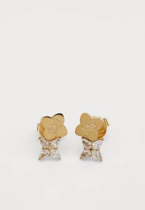 Gouden metalen oorbellen met een bloemmotief en een logo, versierd met vier peervormige heldere kristallen, wat een gelaagd effect creëert.