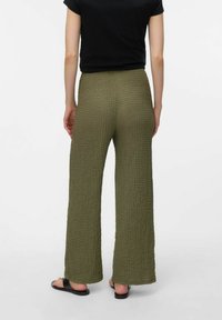 Olive green, textured, wide-leg trousers made from a woven fabric, featuring a high waistband and relaxed fit. The hem is slightly frayed.