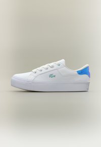 Fehér, alacsony szárú sportcipő sima bőr felsőrésszel, kontrasztos kék díszítéssel a sarokon, lapos fűzőkkel és texturált fehér talppal. Lacoste logóval ellátva.