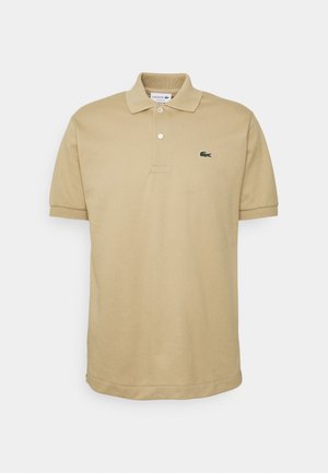 Camisa polo beige de tela de algodón, con un pequeño logo de cocodrilo verde de Lacoste en el lado izquierdo del pecho, con cuello clásico y mangas cortas.
