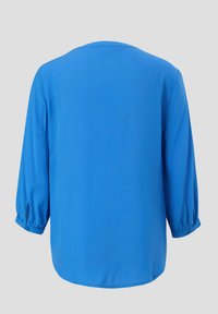 Blauwe blouse van soepele stof met driekwartmouwen, een ronde halslijn en geplooide boorden. Subtiele afgeronde zoom aan de achterkant.