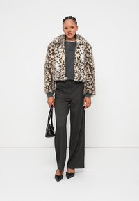 Umjetna krzna jakna s leopard uzorkom i širokim ovratnikom; uparena sivi gornji dio i crne visoke hlače. Crna torba i cipele.