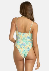 Eén stuk badpak met een bloemenpatroon in tinten blauw, groen en geel. Voorzien van verstelbare dunne bandjes en een hoge beenopening.