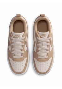 Ζευγάρι από μπεζ και λευκά sneakers Nike με κορδόνια, που φαίνεται από ψηλά σε λευκό φόντο.