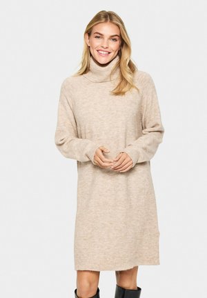 Abito turtleneck beige realizzato in morbido tessuto a maglia. Presenta maniche lunghe e polsini a coste, con una vestibilità rilassata e spacchi laterali all'orlo.