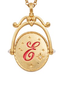 Zlatý náhrdelník s pendantom, ktorý obsahuje kruhový charm s červeným písmenom "E," doplnený malými hviezdami a dvoma perlami po stranách.
