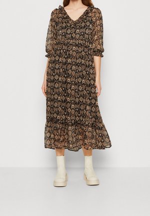 Robe noire longue avec un motif floral, décolleté en V, manches bouffantes et ourlet à volants. Assortie à des bottines crème à la cheville.
