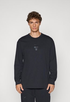 Tricou negru cu mâneci lungi, din bumbac, cu un logo texturat cu un taur și swoosh-ul Nike plasat central. Design simplu, cu guler rotund.