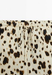 Szorty z elastycznym paskiem w leopardzi wzór z zapięciem na sznurek, wykonane z miękkiego, lekkiego materiału w beżowych i brązowych odcieniach.