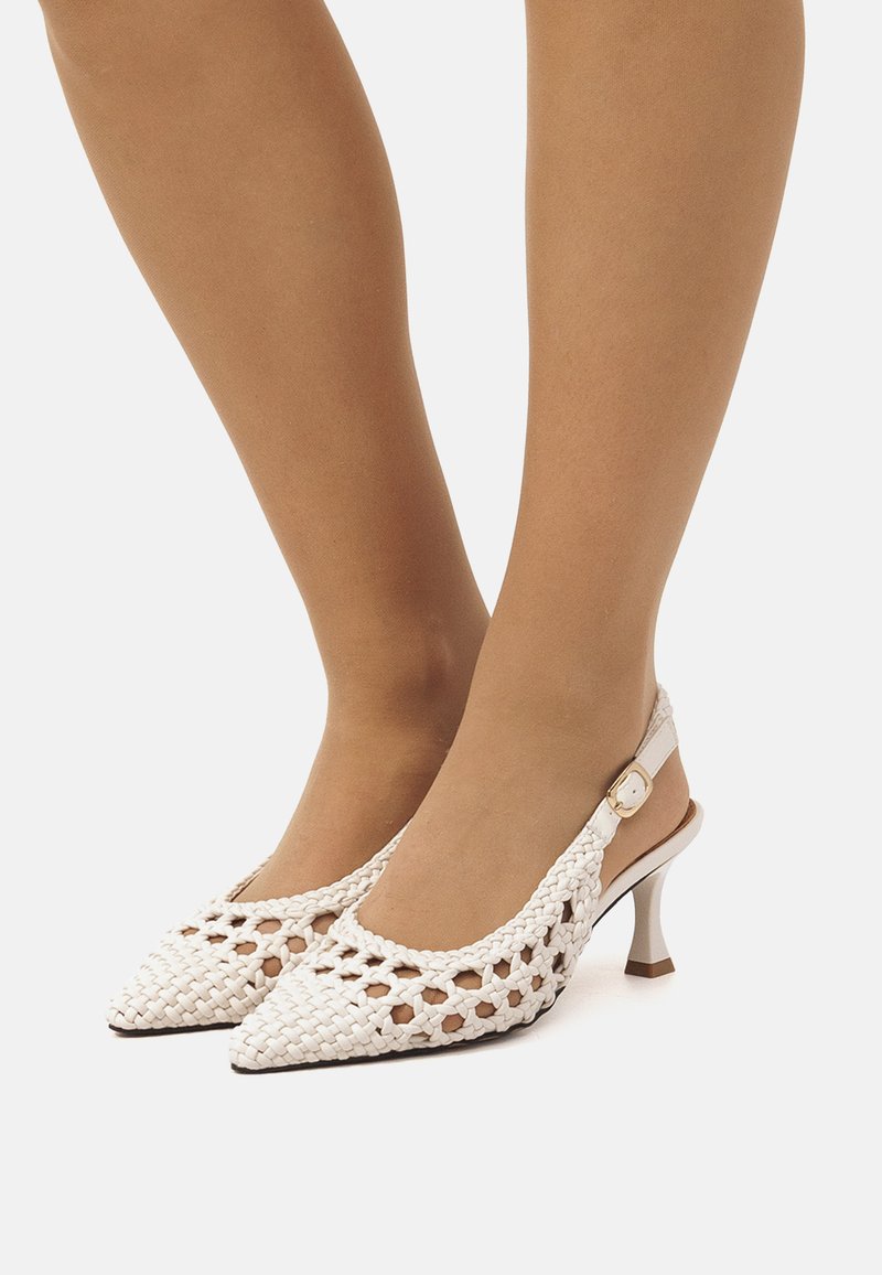 Talons hauts à bride tissée blanche avec un bout pointu, une sangle décorative et un petit talon aiguille, présentant un design supérieur texturé et respirant.