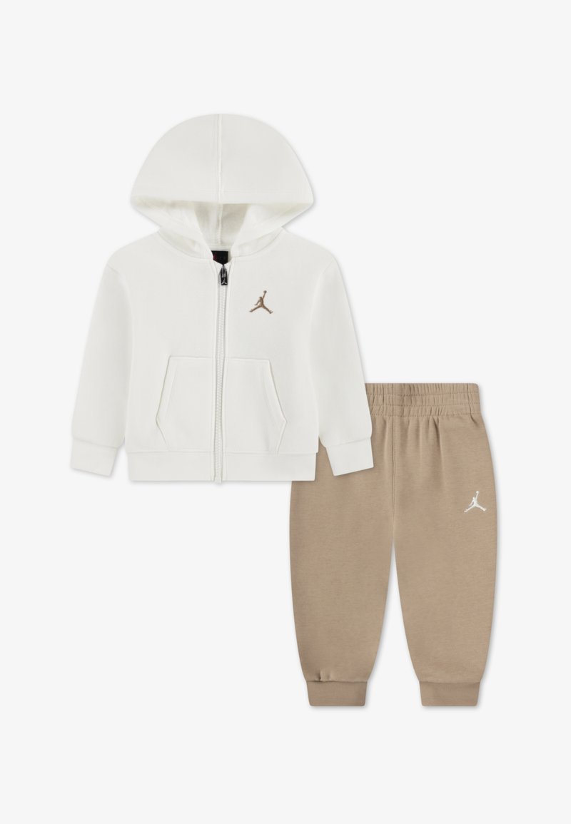 Witte hoodie met ritssluiting en een kangoeroezak, gecombineerd met beige joggingbroek. Beiden hebben Jordan-logo accenten en een zachte, gladde textuur.