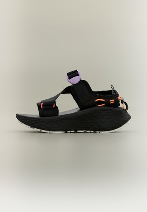 Black sandal with adjustable fabric straps, featuring purple and orange accents. Textured sole with a cushioned, sculpted design.