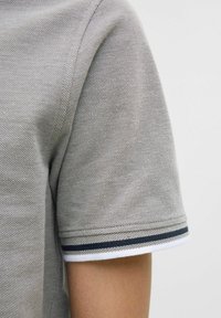 Grijze polo shirt van gestructureerde stof, met korte mouwen en contrasterende witte en marineblauwe strepen bij de kraag.