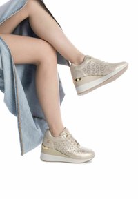 Sneakers platform beige con design perforato, finiture metallizzate e texture liscia. Presentano una suola in gomma bianca.