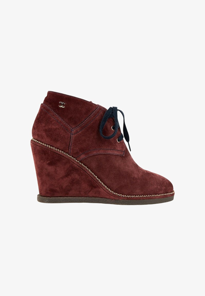Bottine compensée en daim bordeaux avec lacets noirs, détail chaîne dorée sur la semelle et petit logo double C entrelacé près de la cheville.