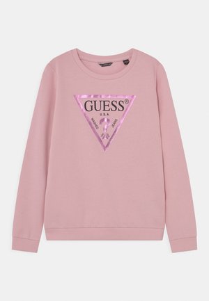 Sweatshirt rose à manches longues avec col rond, orné d'un logo triangulaire violet brillant au centre avant, portant l'inscription "GUESS U.S.A. Washed Jeans".