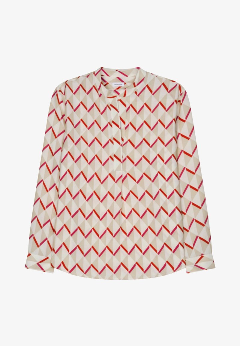 Blouse crème à manches longues avec motif géométrique chevron rouge et beige et petit col mandarin, patte de boutonnage à l'avant.