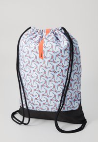 Mochila con cordón que presenta un patrón geométrico en azul, rojo y blanco, con un fondo negro sólido y un acento naranja en la parte superior.