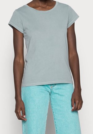 Lysegrå bomuld T-shirt med rund halsudskæring, op-rullede korte ærmer og en afslappet pasform. Båret med lyseblå denimjeans.