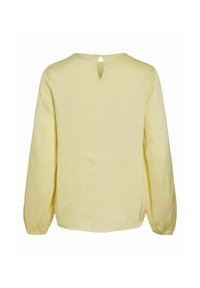 Vaaleankeltainen pitkähiha blouse, jossa on nappikiinnitys avaus yläselässä ja joustavat hihansuut.