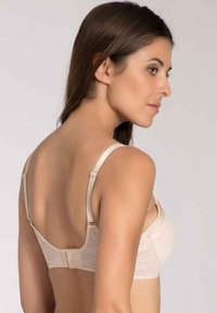 Beżowy biustonosz z gładkiego materiału, szerokimi ramiączkami i zapięciem na haftkę. Posiada subtelny wzór geometryczny i bezszwowy krój z tyłu.