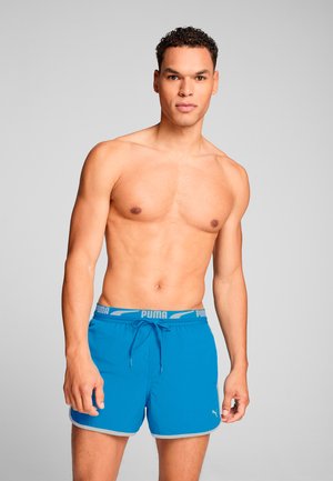 Bañadores azules con cintura elástica, que cuentan con un cordón, detalles grises y un pequeño logo blanco de Puma en la pierna izquierda.