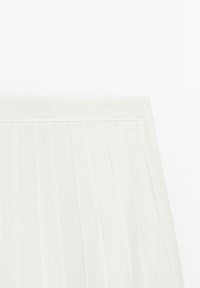 Tissu plissé blanc avec une texture lisse, présentant une taille unie. Le design se compose de plis verticaux s'étendant vers le bas.