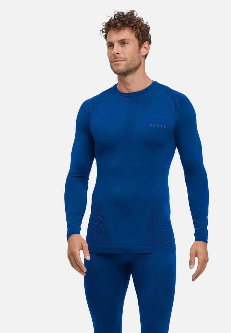 Haut de sport à manches longues bleu en tissu extensible, avec des accents texturés et une coupe ajustée. Logo affiché sur la poitrine.