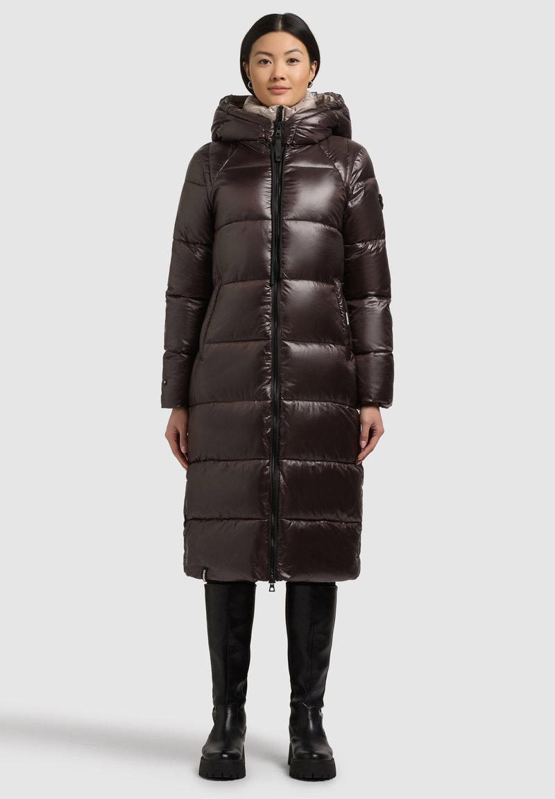 Langer, voluminöser dunkelbrauner Daunenmantel mit Reißverschluss, hohem Kragen und Kapuze. Glattes, glänzendes Material mit markanten Nähten und seitlichen Taschen.