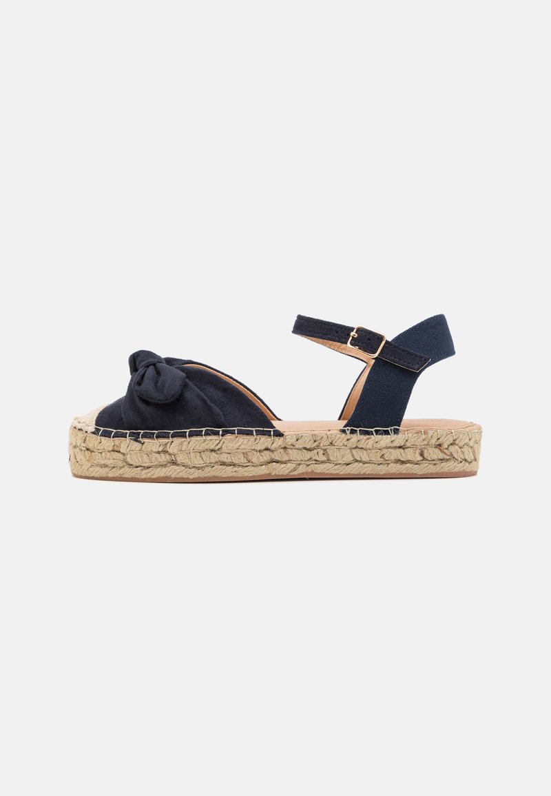 Ναυτικό μπλε σανδάλι espadrille με δέσιμο από ύφασμα, πλατφόρμα περιτυλιγμένη με φυσικό ίνα, και λουράκι στον αστράγαλο που ασφαλίζει με μεταλλική αγκράφα.