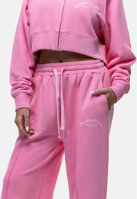 Roze cropped sweatshirt met een rits en bijpassende roze sweatpants met een elastische tailleband en zijzakken. Textlogo-detail.