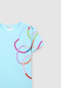 T-shirt azzurro a maniche corte con linee astratte colorate che si avvolgono in rosso, rosa, verde e blu. Tessuto morbido, vestibilità classica.