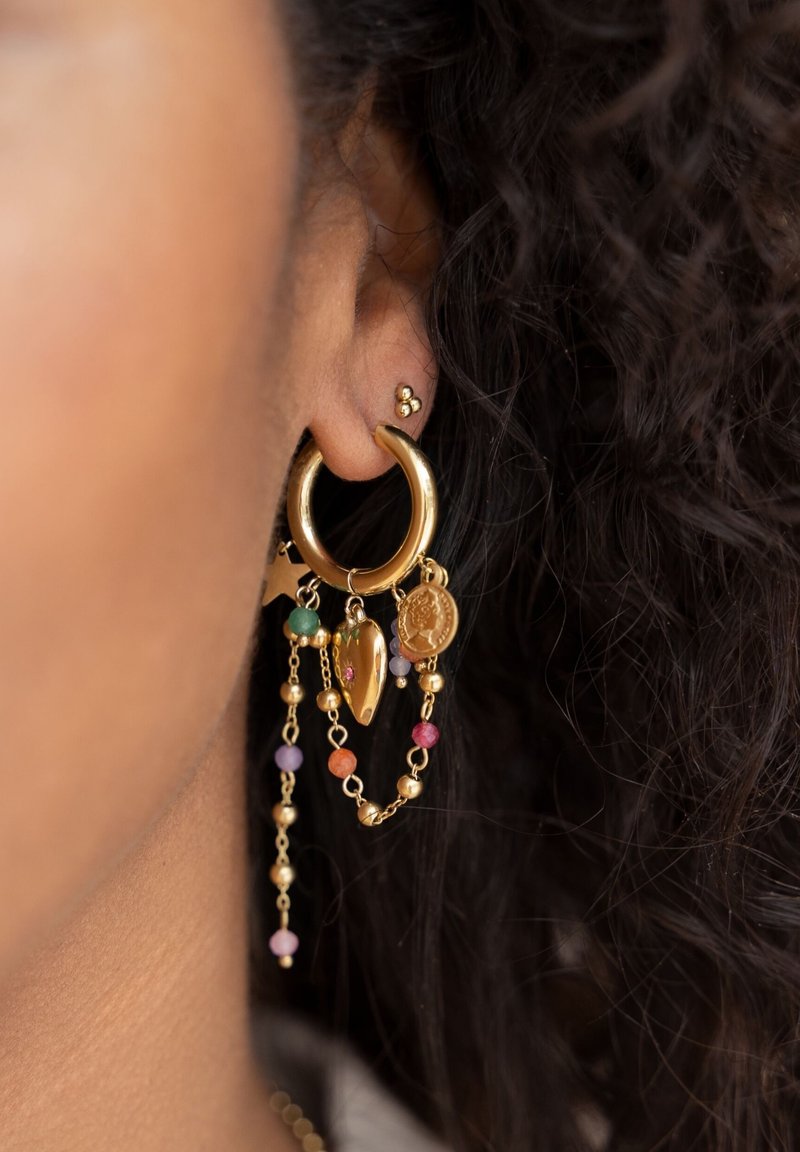 Boucle d'oreille en or avec des charms suspendus, comprenant des perles de différentes couleurs, une forme de cœur et une pièce décorative, pendue à une chaîne.