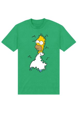 Groen T-shirt met een afbeelding van een cartoonman met gele huid en een witte shirt die achteruit in groene struiken gaat.