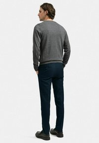 Grå tröja med ribbade mudd, kombinerad med mörkblå byxor. Byxorna har en bakficka och är skräddarsydda för en smal passform.