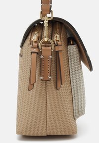 Sac tissé beige avec des accents en cuir, fermetures éclair doubles et quincaillerie dorée. Un côté présente un panneau texturé gris clair. Design avec rabat en haut.