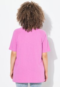 Camiseta de manga corta rosa con un corte relajado y un dobladillo redondeado, que presenta una textura suave y un diseño de manga raglán.