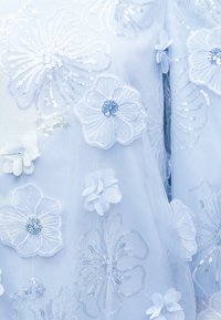 Jasnoniebieska tkanina z białym haftem i cekinowymi wzorami kwiatowymi oraz aplikacjami kwiatów 3D na przezroczystym tiulu.