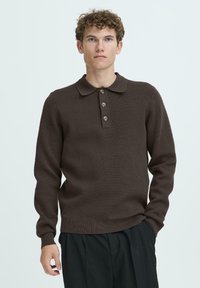 Brauner gestrickter Polo-Pullover mit Kragen, vier Knöpfen, langen Ärmeln und gerippten Bündchen und Saum. Einfaches, strukturiertes Stoffdesign.