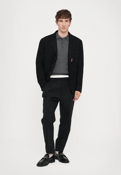 Mustam blazer hall grey polo särk, mustad püksid ja läikivad mustad loaferid kuldsete aktsentidega. Puhtad jooned, täpselt sobiv ja peened tekstuurid.