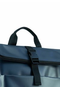 Mochila impermeable de color azul marino con un asa superior, correa ajustable, cierre de cremallera y un broche de plástico. Textura suave y brillante.